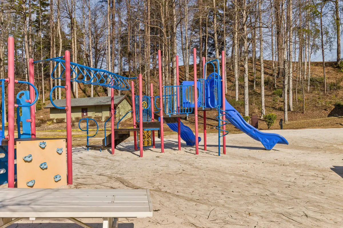 A vibrant playground with colorful equipment and a sandy play area, nestled amid leafy trees. Children are seen playing, and the space exudes an atmosphere of laughter and energetic activity, ideal for younger family members.