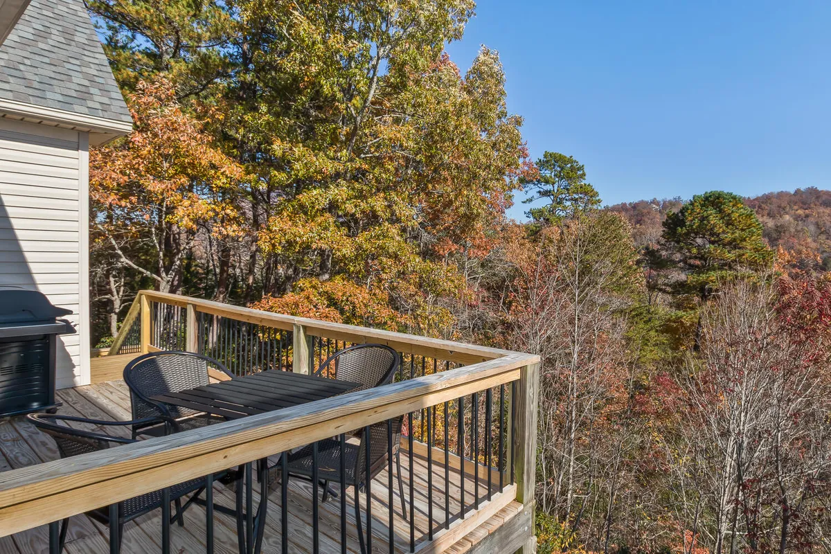 A peaceful lower deck area with a table and chairs surrounded by trees, providing a tranquil outdoor setting that overlooks nature. The deck invites guests to relax, watch for wildlife, or soak in the mountain serenity.