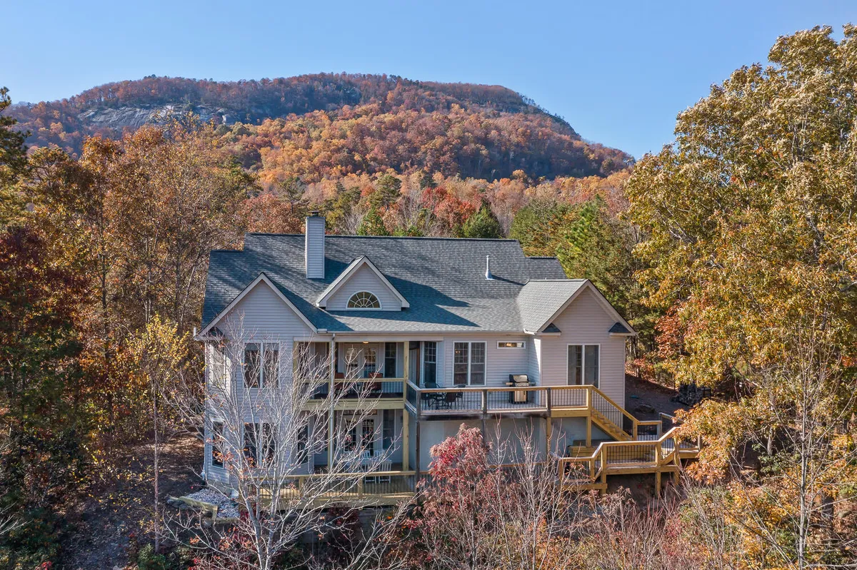 This image captures the house with an expansive deck overlooking a stunning mountain backdrop and vibrant fall foliage. The scene exudes tranquility and invites the viewer to imagine relaxing mornings with coffee or serene evenings surrounded by natural beauty.