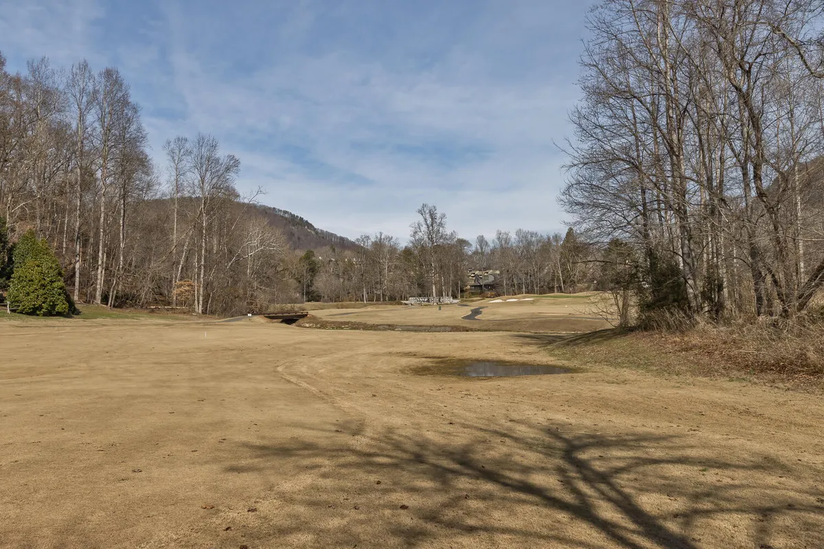 A sweeping view of the championship golf course framed by bare trees and majestic mountains in the background. The wide, open space is perfect for leisurely walks or enjoying a round of golf in a serene environment.