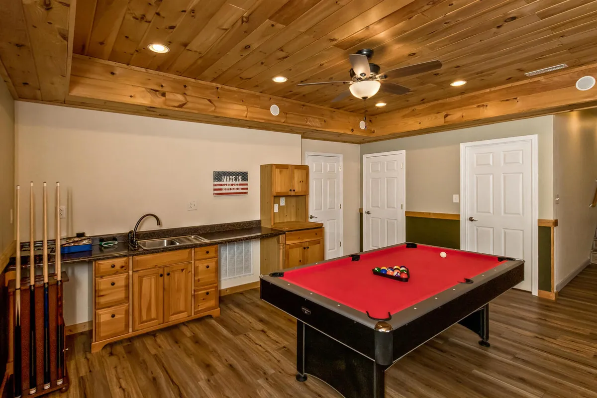 A dedicated indoor leisure space featuring a pool table, kitchenette, and wooden ceiling, set up for both fun and casual gatherings. The room is designed for relaxation and entertainment, perfect for hosting game nights or taking breaks from work.